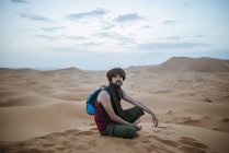 Turista con turbante sentado en el desierto - foto de stock