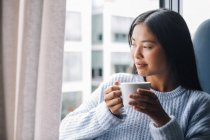 Femme avec tasse debout devant la fenêtre — Photo de stock