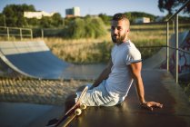 Скейтбордист сидит в скейтпарке — стоковое фото