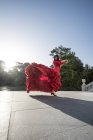 Женщина, одетая в красное фламенко на террасе на заднем плане — стоковое фото