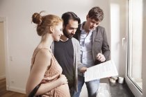 Real estate agent showing expecting parents contract in new apartment — Stock Photo