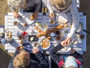 Family sitting on table outdoors and having breakfast — Stock Photo