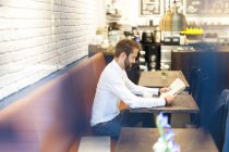 Бизнесмен сидит в кафе и читает газету — стоковое фото