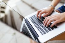 Hands of woman typing on keyboard of laptop — Stock Photo