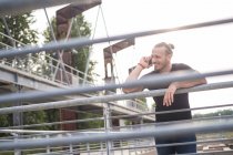 Усміхнений чоловік на телефоні спирається на перила — стокове фото