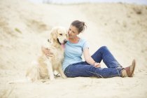 Junge Frau mit Hund im Sand — Stockfoto