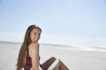 Smiling young woman sitting on the beach — Stock Photo