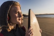 Ragazza adolescente sulla spiaggia che trasporta tavola da surf — Foto stock