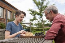 Отец и сын играют в шахматы в саду — стоковое фото
