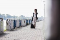 Mujer de negocios con equipaje hablando en smartphone - foto de stock
