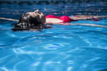 Женщина, плывущая по воде бассейна — стоковое фото