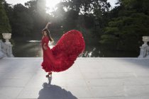Femme vêtue de flamenco dansant en rouge sur une terrasse devant un lac — Photo de stock