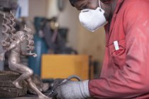 Homme travaillant sur figurine en bronze, vue latérale — Photo de stock