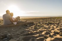 França, Bretagne, Finistere, península de Crozon, casal sentado na praia, desfrutando do pôr do sol — Fotografia de Stock