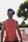Улыбающийся спортсмен на тартанской трассе в очках виртуальной реальности — стоковое фото