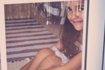 Ritratto di bambina sorridente seduta dietro la finestra — Foto stock