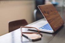 Wooden laptop, smartphone and glasses — Stock Photo