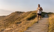 Іспанія, Авілес, спортсмен людина біжить вздовж прибережних стежок на заході сонця — стокове фото