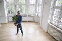 Чоловік тримає рослина в квартирі порожній — стокове фото