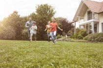Famiglia spensierata che corre in giardino — Foto stock
