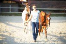 Giovane donna alla guida di due cavalli — Foto stock