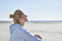 Jeune femme profitant du soleil sur la plage — Photo de stock
