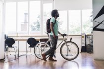 Homem com mochila empurrando bicicleta — Fotografia de Stock