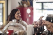 Cliente recebendo café no saco no balcão de um café — Fotografia de Stock