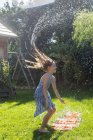 Chica divirtiéndose con cojín de agua inflable en el jardín - foto de stock