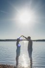 Paar steht am Cospudener See und formt Herz mit Händen gegen die Sonne — Stockfoto