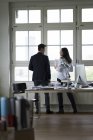 Homme d'affaires et femme debout à la fenêtre du bureau, désamorçant — Photo de stock