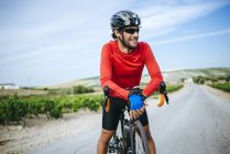 Ciclista sorridente uomo con bicicletta in piedi sulla strada — Foto stock
