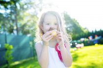 Little girl eating muffin in the garden — Stock Photo