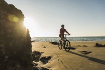 Francia, penisola di Crozon, donna in bicicletta sulla spiaggia — Foto stock