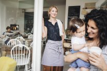 Lächelnde Frau im Café mit Kunden — Stockfoto