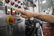 Hombre presionando botón en planta embotelladora de cerveza - foto de stock