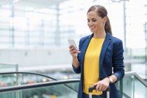 Smiling woman at a station looking on cell phone — Stock Photo