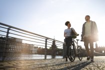 Coppia a piedi lungo il fiume, spingendo in bicicletta — Foto stock