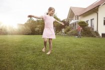 Ragazza che balla in giardino con la famiglia sullo sfondo — Foto stock