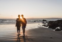 Frankreich, Halbinsel Corzon, Paar spaziert am Strand bei Sonnenuntergang — Stockfoto