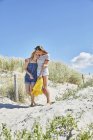Two happy female friends walking in dunes at the beach — Stock Photo