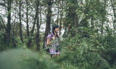 Lächelnde junge Frau mit Rucksack spaziert im Wald — Stockfoto