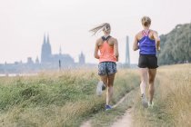 Two young women running on field path — Stock Photo