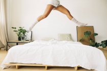 Piernas femeninas saltando en la cama - foto de stock