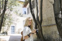 Portrait de femme blonde avec caméra dans la rue — Photo de stock