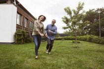Heureux mature couple courir dans jardin — Photo de stock