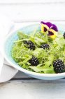 Bowl of wild-herb salad with edible flower and blackberries — Stock Photo