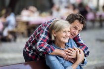 Счастливая милая старшая пара обнимается на скамейке в парке — стоковое фото