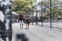 Two friends walking with basketball outdoors — Stock Photo