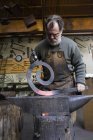 Schmied in seiner Werkstatt beim Hämmern von Metalldetails — Stockfoto